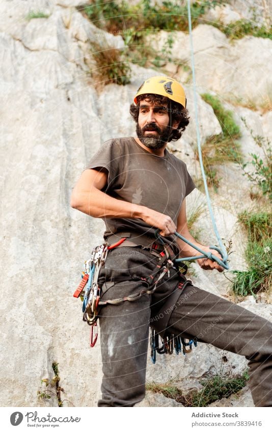 Man in safety harness near rock climber man prepare extreme adventure equipment male carabine activity mountain forest belt active explore rope cliff challenge