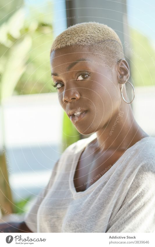 Black woman standing looking at camera relax having fun sunny using female ethnic black african american smile modern unemotional casual young short hair enjoy