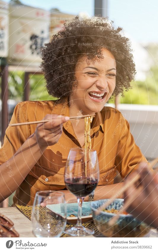 Delighted black woman eating in Asian cafe asian food restaurant laugh noodle chopstick oriental having fun female african american ethnic table meal lunch