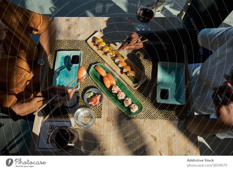 Crop black women at table with sushi in restaurant roll woman asian food cafe eat various assorted set ethnic african american dish tasty delicious meal