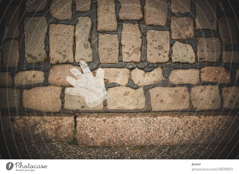 A disposable plastic glove lies on the cobblestone pavement disposable glove throwaway society Cobblestones Environmental pollution Trash Polluter