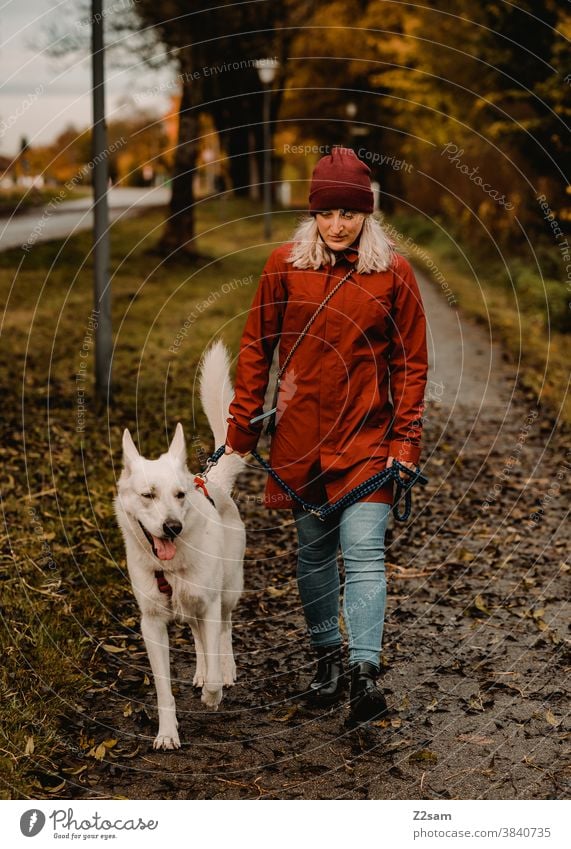 Young woman walking a white shepherd dog Walk the dog Dog Shepherd dog stroll White Affection upbringing Red Cap Autumn Field Nature Rural Sit leash