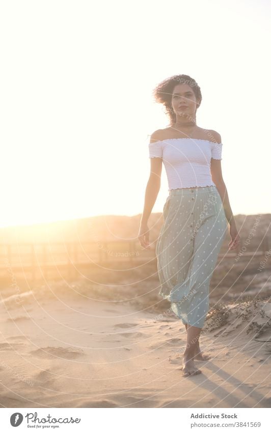 Serene woman walking on sandy beach at sunset carefree summer barefoot grace tranquil female outfit hill nature charming enjoy sundown freedom young smile