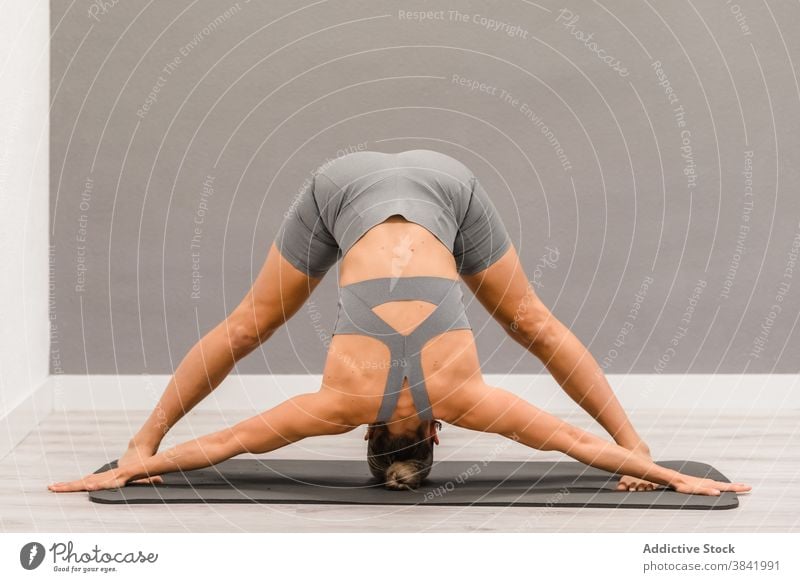 Slender woman doing yoga in Downward Facing Dog position downward facing dog pose yogi flexible stretch asana adho mukha svanasana mat home female barefoot