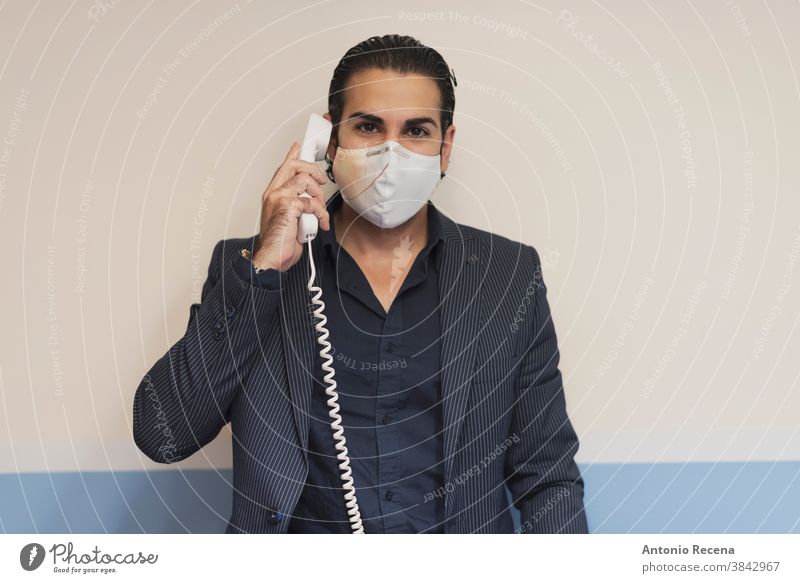 Suit man at phone looking at camera cable covid-19 coronavirus business men communication sale salesman telemarketing mask surgery indoor suit elegance people