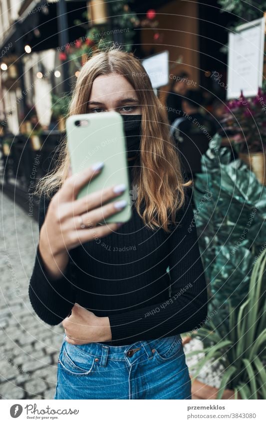 Young woman having video call talking while walking downtown wearing the face mask to avoid virus infection care caucasian chat contagious corona coronavirus