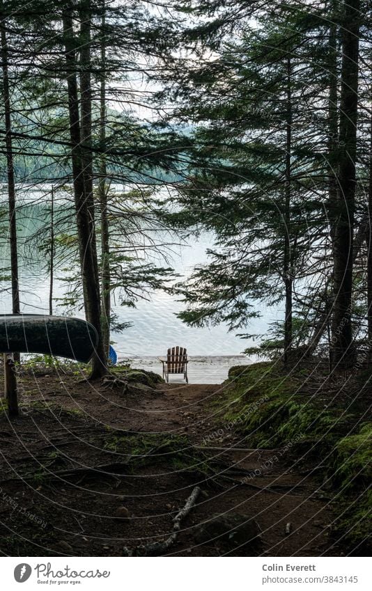 Adirondack Chair by lake with canoe in foreground adirondack chair relaxing Adventure Canoe trip Summer Vacation & Travel Lake Nature Water Day