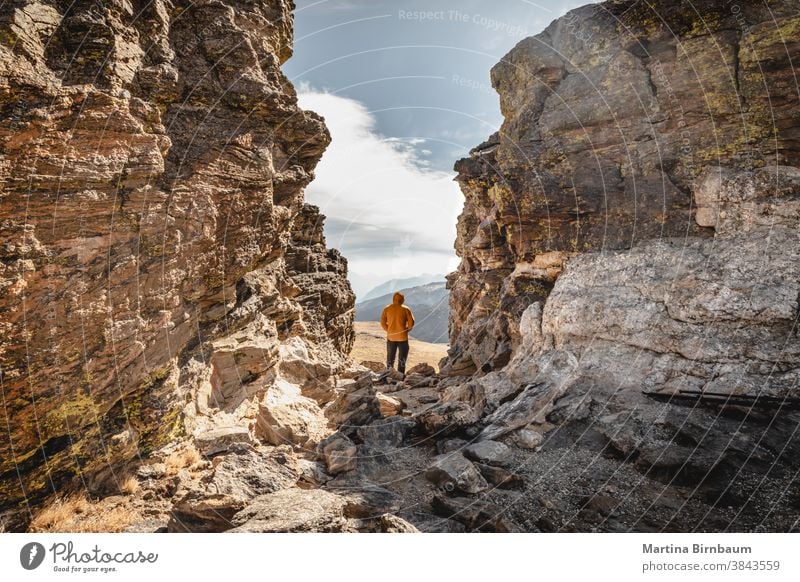 Man standing on a summit  between rocks in the Rocky Mountain National Park and looking over the mountain range on a coldand windy day traveller winter