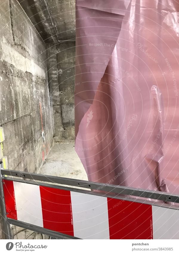 A purple plastic sheet hangs behind a barrier fence in front of a concrete wall. Construction site, security tarpaulin Control barrier cordon Wall (barrier)