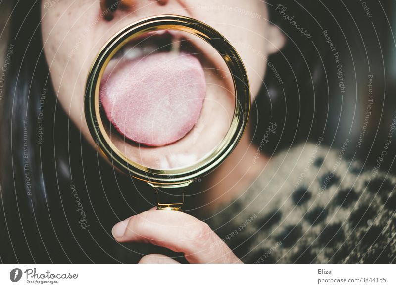 Woman licks a magnifying glass with her tongue. Magnifying glass Tongue taste Sense of taste Enlarged Investigate stick out one's tongue Stick out