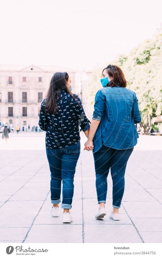 couple of women with a face mask walking hand in hand lesbian homosexual covid 19 female love holding hands together romantic girlfriend happiness romance