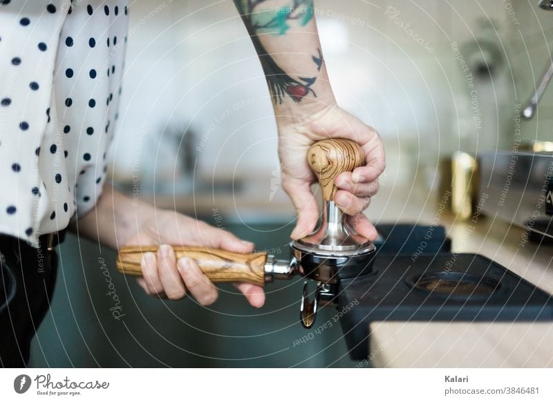 Tattooed barista presses the espresso powder into the portafilter with a tamper Espresso Coffee Café screen carrier Woman prepare Close-up Hand Craft (trade)