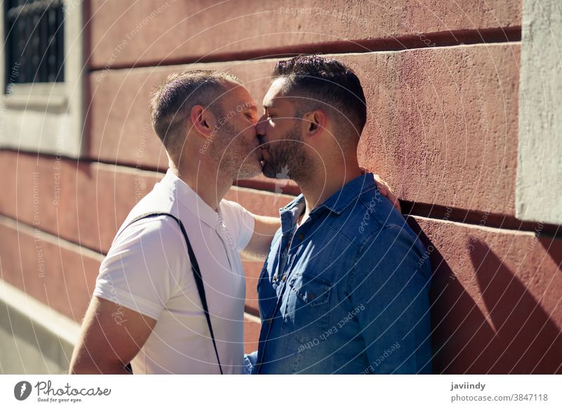 Gay couple kissing outdoors in urban background. gay men male love homosexual lgbt lgbtq relationship lovers boyfriend people adult wall happy outside together