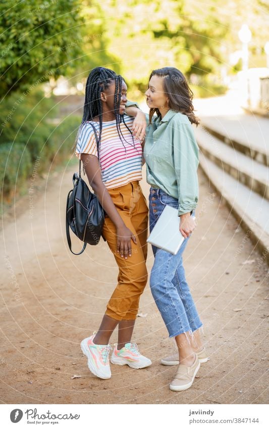 Two multiethnic women posing together with colorful casual clothing woman friend tablet digital female girl young lifestyle urban beautiful device outside lady