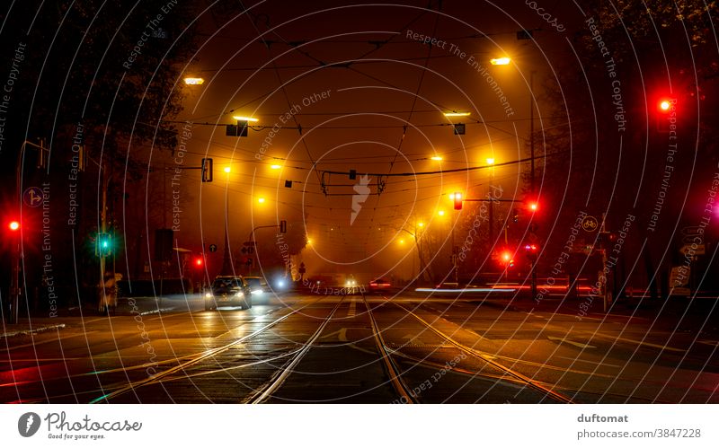 Long-term exposure of an intersection at night Traffic light out Town Light blurred background Evening Night life Street cross trees Car Fog Mobility