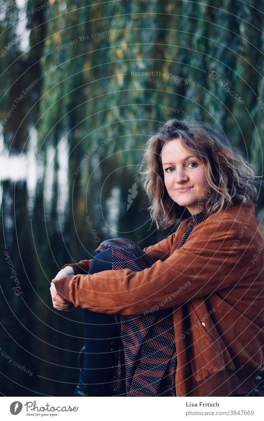 WOMAN - SITTING - WEEPING WILLOW - REFLECTION Woman Curl 30-35 years old Adults Blonde Autumn Weeping willow Skeptical Neutral Water Reflection in the water