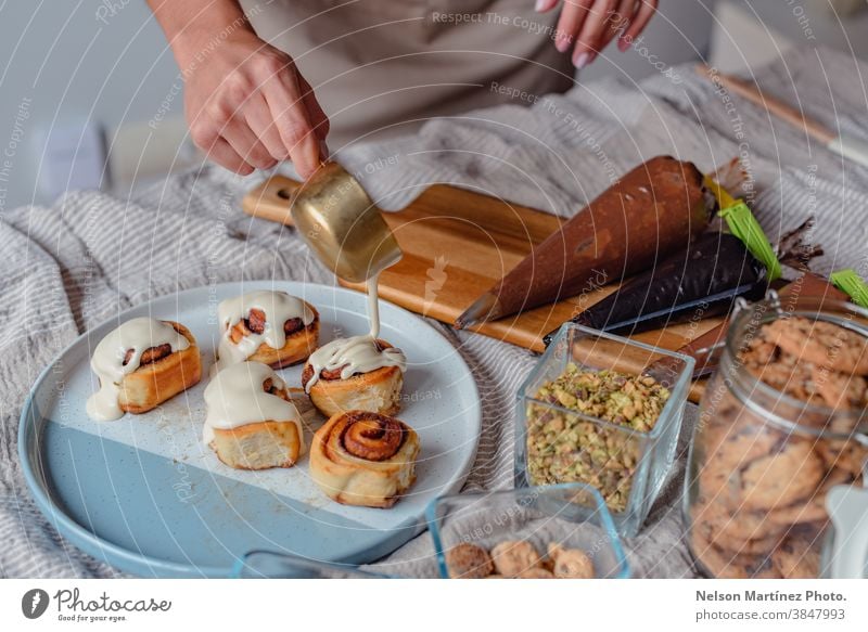 Woman preparing and decorating cinnamon rolls. adult indoor cooking dough flour chef restaurant employment food Eggs bakery desserts butter salt home home made