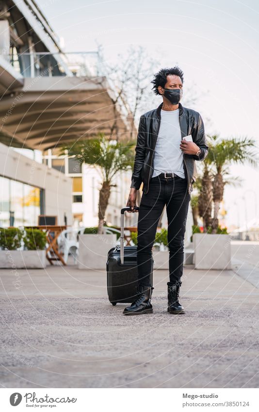 Tourist man carrying suitcase while walking outdoors. afro tourist traveler destination concept travelling holiday joy enjoy adventure traveller vacations