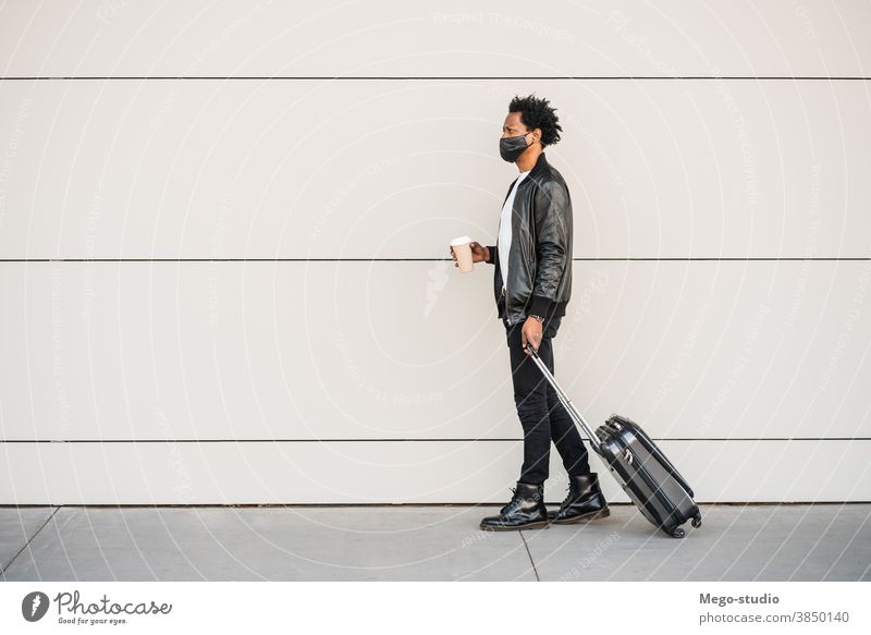 Tourist man carrying suitcase while walking outdoors. afro tourist traveler destination concept travelling holiday joy enjoy adventure traveller vacations