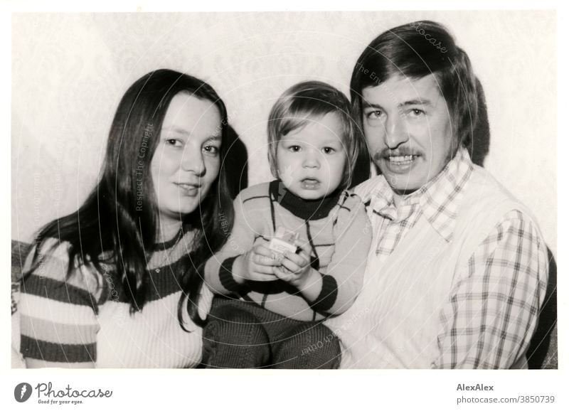 Black and white portrait of a young family - mother and father holding a toddler in their arms and looking into the camera Family Mother Father Child Toddler