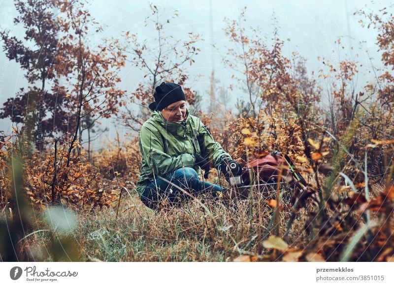 Woman with backpack having break during autumn trip drinking a hot drink from thermos flask on autumn cold day outdoors destination hiking holiday vacation