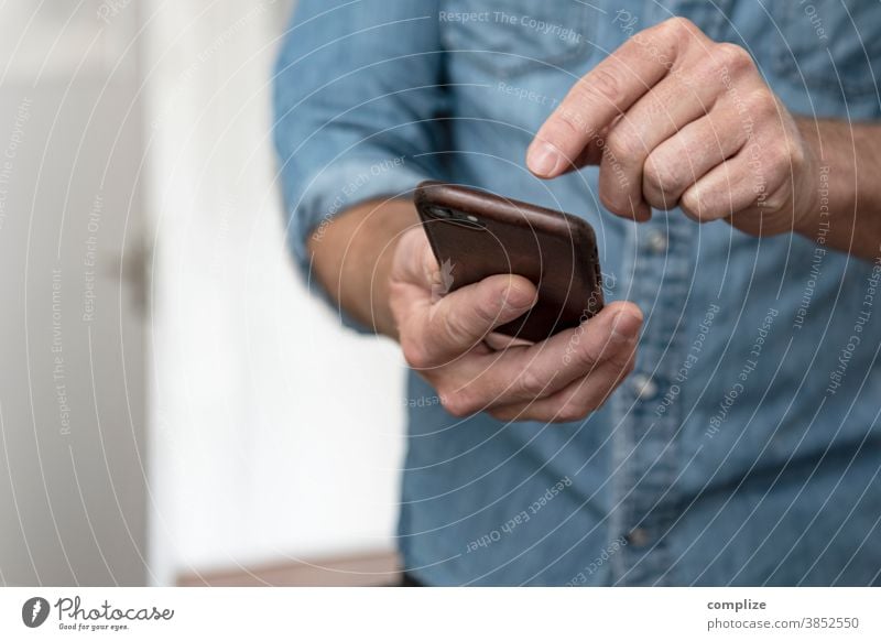 Man types into his smartphone - Smarthome Interior shot Colour photo Media Typing To call someone (telephone) Communicate Home page Transmit Internet