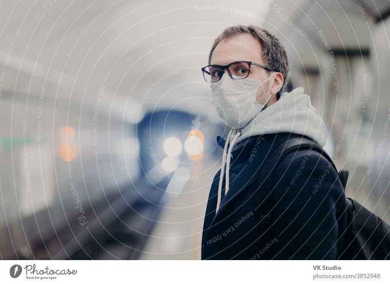 Coronavirus crisis. Male follows quarantine rules wears protective medical mask, travels in public transport cares about health during epidemic or pandemic. Danger of catching virus in city transport