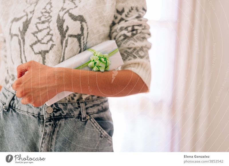 Young unrecognizable woman holds in a gift box in white paper with green twine. Christmas New Years present. christmas merry christmas new year