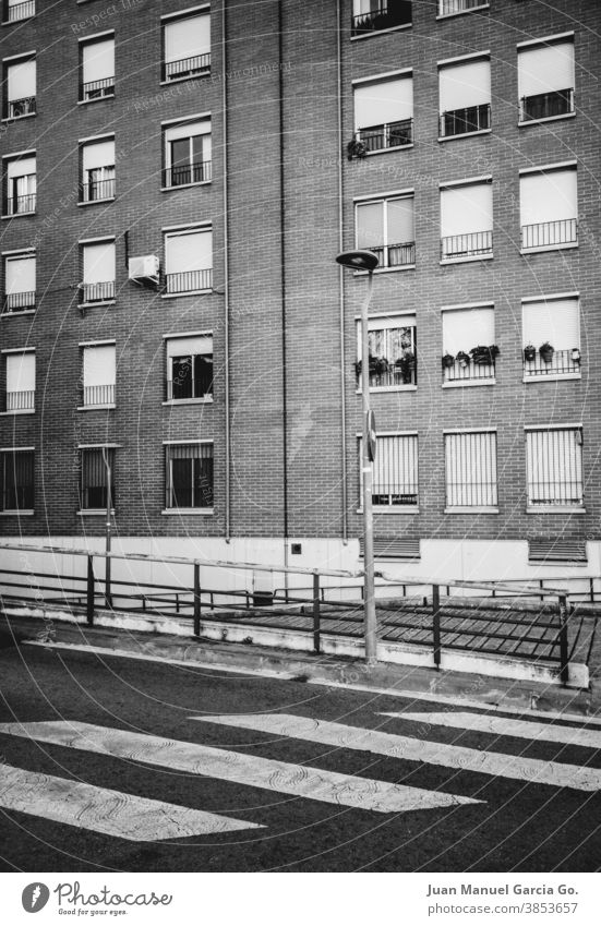 Suburban neighborhood housing block in black and white windows zebra crossing brick dwellings flats humble protection street sidewalk blinds house facade