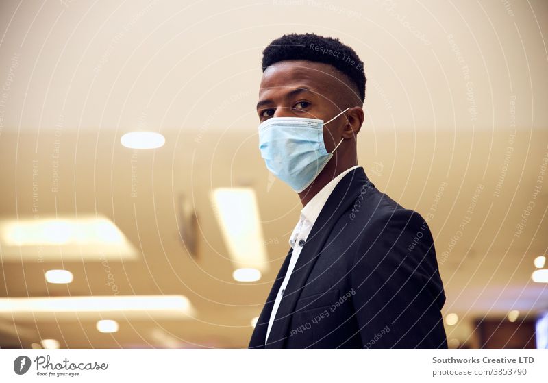 Portrait Of Young Businessman Wearing Mask Standing In Modern Office During Health Pandemic business businessman face mask face covering wearing ppe working