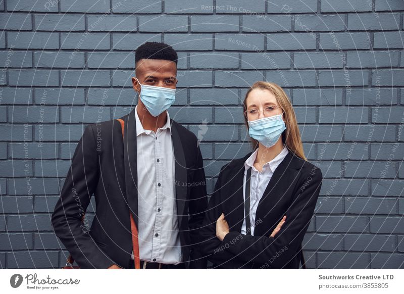 Portrait Of Business Couple Wearing Masks Standing By Wall Outside Office During Health Pandemic business businessman businesswoman face mask face covering