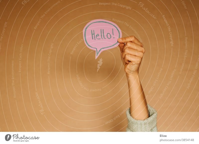 Hand holds a speech bubble in which Hello! stands. Greetings in English. salute sb. Speech bubble hello Foreign language Communicate Language communication Hi