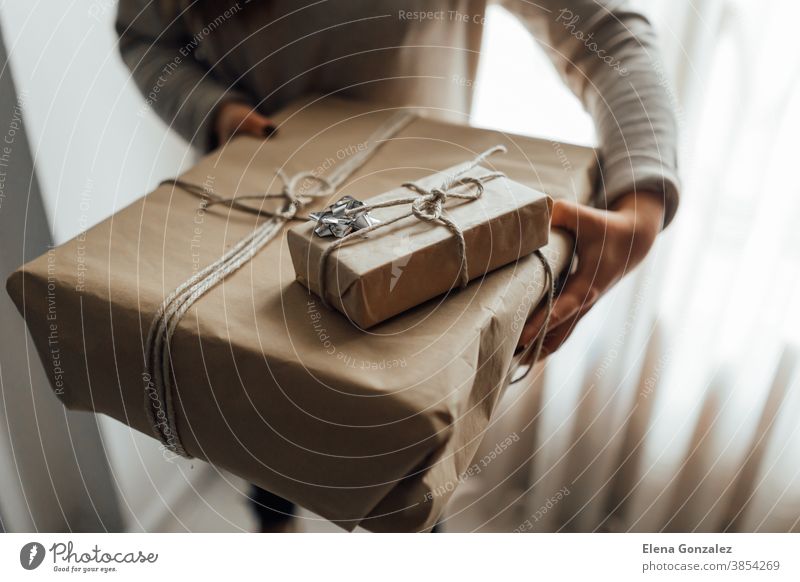 Young woman holds in hands stacked Christmas gift boxes in craft paper with juniper. Christmas presents concept. christmas merry christmas new year women