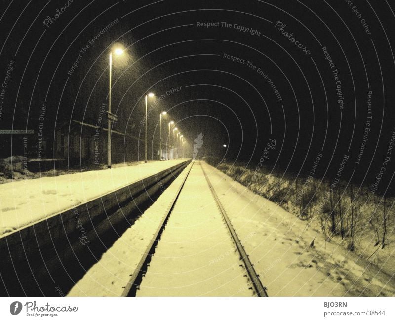 The train is coming Lamp Winter Platform Railroad tracks Night Cold Empty Transport Train station Floodlight Light Snow