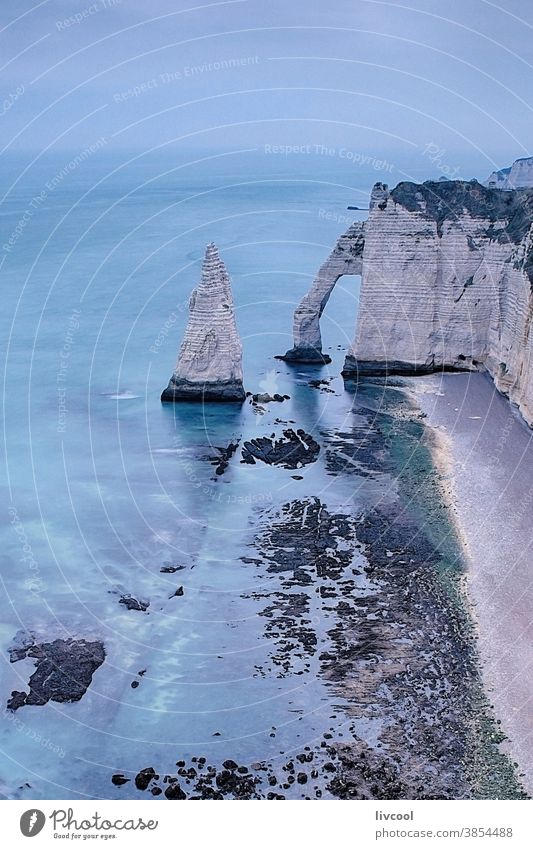 view of the cliff of etretat, normandy porte daval landscape blue romantic nostalgic blue hour la porte damont coast beach cliffs scene clouds sea seashore