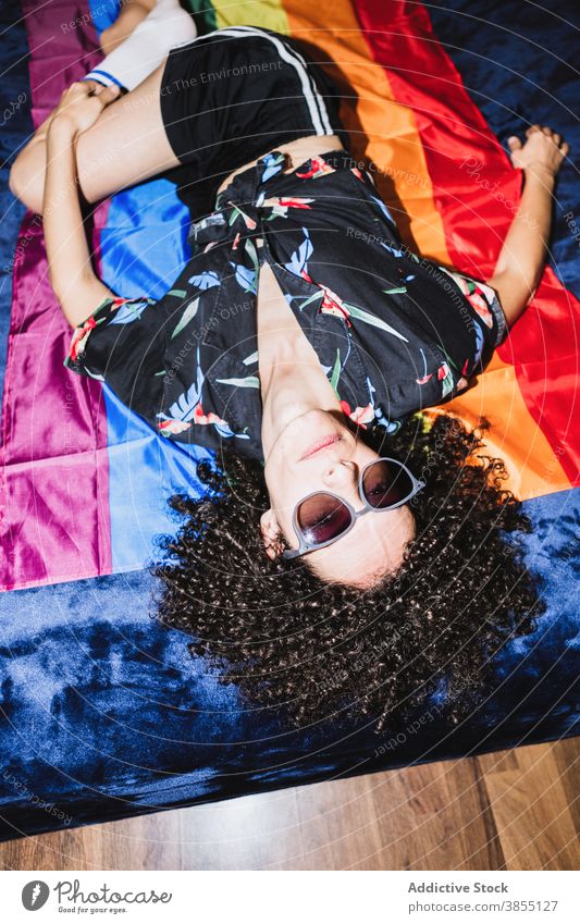 Relaxed female lying on LGBT flag on bed woman equal rainbow homosexual respect tolerance upside down right community gender solidarity same sex discriminate