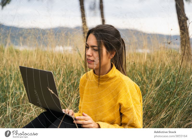 Thoughtful woman working on laptop in meadow freelance remote field countryside project autumn female blanket job internet pensive gadget computer busy watch