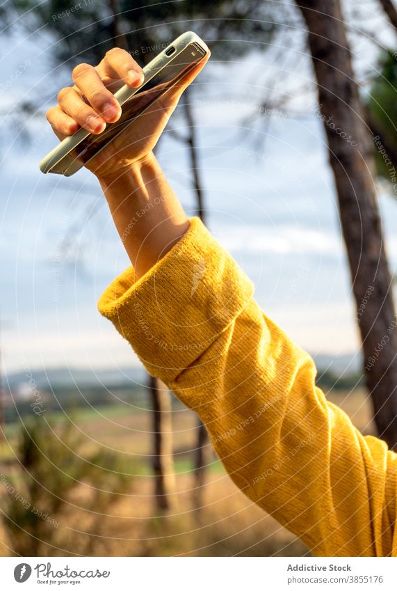 Anonymous woman taking selfie in meadow in fall autumn relax smartphone self portrait weekend enjoy female sweater yellow dry field device gadget nature