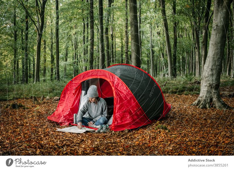 Woman reading paper map near camping tent navigate woman campsite forest orientate search female vacation nature tourist explore destination journey trip