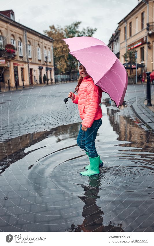 Little girl holding big pink umbrella walking in a downtown on rainy gloomy autumn day raining outdoors little seasonal fall childhood beautiful weather outside