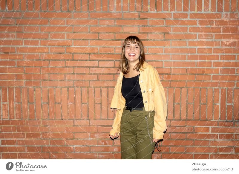 Beautiful young woman stands near an old brick wall in the city at night standing attractive smiling happy casual attire female person beautiful lifestyle