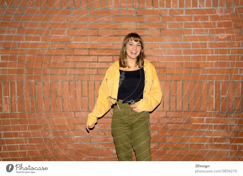 Beautiful young woman stands near an old brick wall in the city at night standing attractive smiling happy casual attire female person beautiful lifestyle