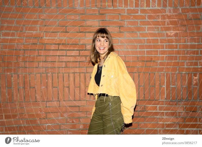 Beautiful young woman stands near an old brick wall in the city at night standing attractive smiling happy casual attire female person beautiful lifestyle