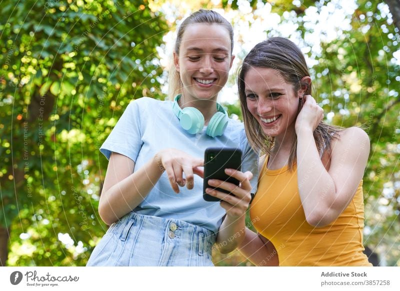 Female hipsters with smartphone walking in city girlfriend using discuss street share together mobile cheerful laugh happy urban show demonstrate gadget device