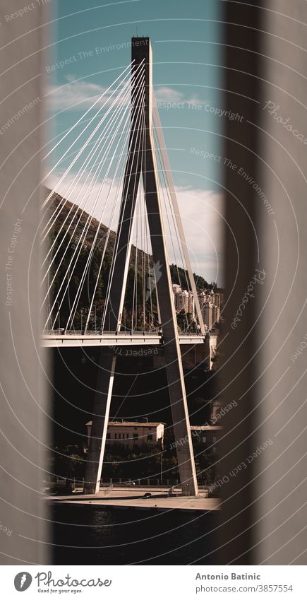 Vertical moody shot of the bridge at the entrance of Dubrovnik city, framed between two white fence pillars above adriatic aerial architecture bay blue boat