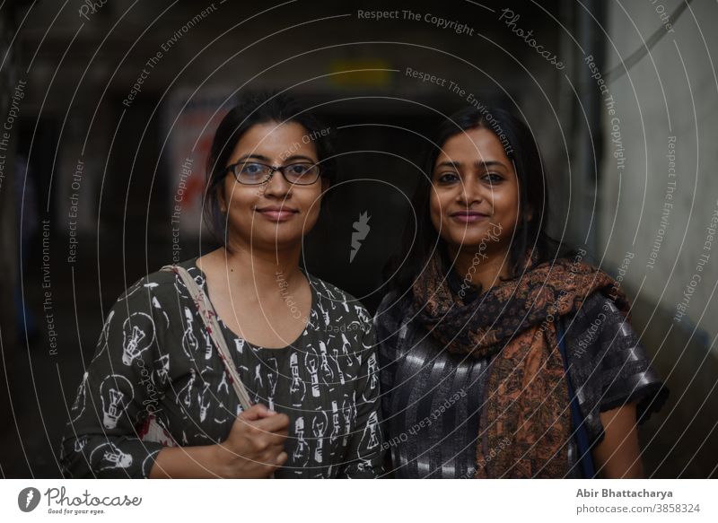 Portrait of two Indian Bengali brunette women/friends/sisters standing in a street/lane of Bengal. Indian lifestyle actress adult asian attractive background