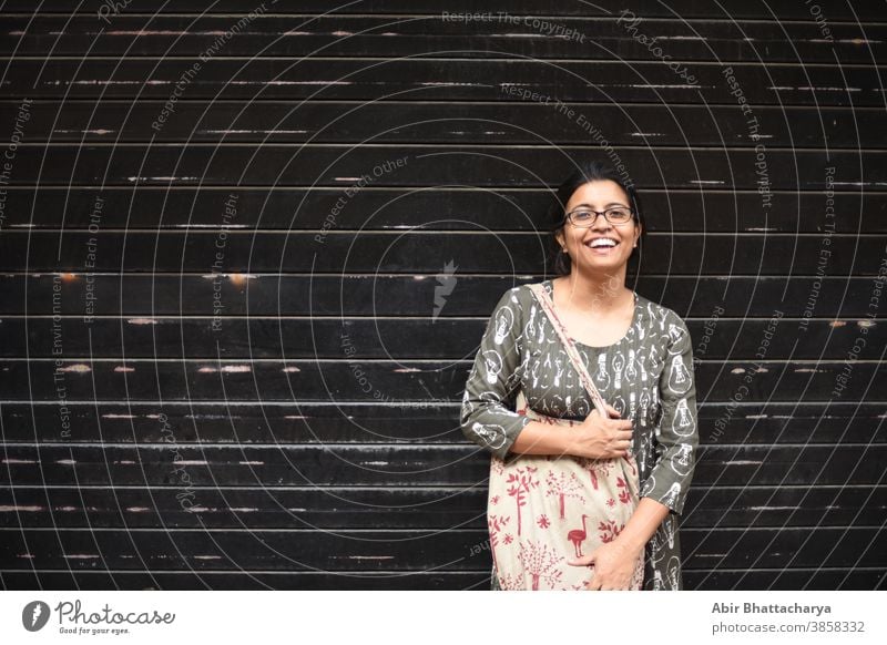 Portrait of an Indian Bengali brunette woman in front of a wall/ metallic gate/ black textured background. Indian lifestyle actress adult asian attractive