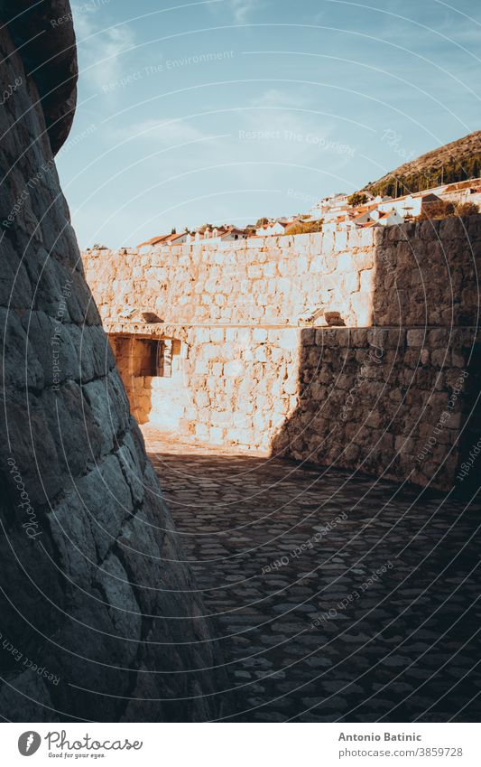 Looping circle area surrounded by walls around the Minceta castle tower in the old city of Dubrovnik being lit by strong sunlight and creating shapes with shadows