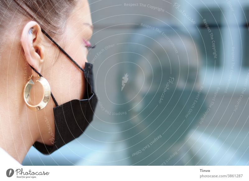 Young Woman With Black Mouth Nose Covering Looks At Herself In A Windowpane reflection Reflection Face Face mask Mouth and nose cover Mask mouth-nose protection