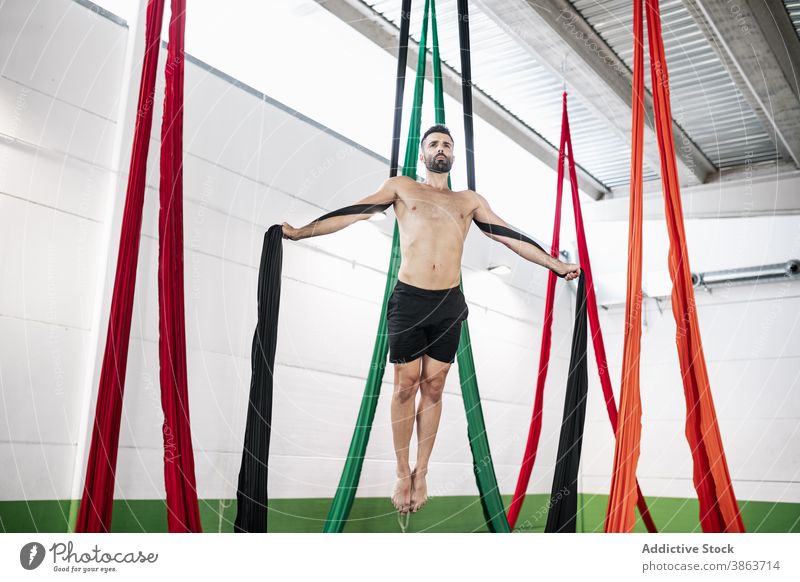 Bearded dancer balancing on aerial silks man balance studio rehearsal gymnastic acrobatic hang male shirtless ribbon adult fabric barefoot skill flexible